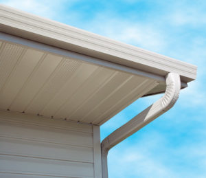 View of white seamless gutters affixed to home. Blue skies in background,