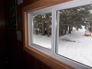 Interior view of sliding window with white frames overlooking snowy landscape.