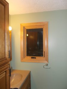 View of bathroom with pastel-colored walls and a wood-frame casement window.