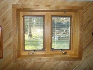 Interior view of wood frame casement windows overlooking yard.