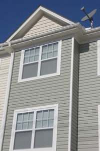 Residence with white frame windows and gray seamless siding. Blue skies in background.