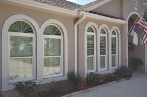 Exterior of home with five large double hung windows, each topped with a specialty shape window.